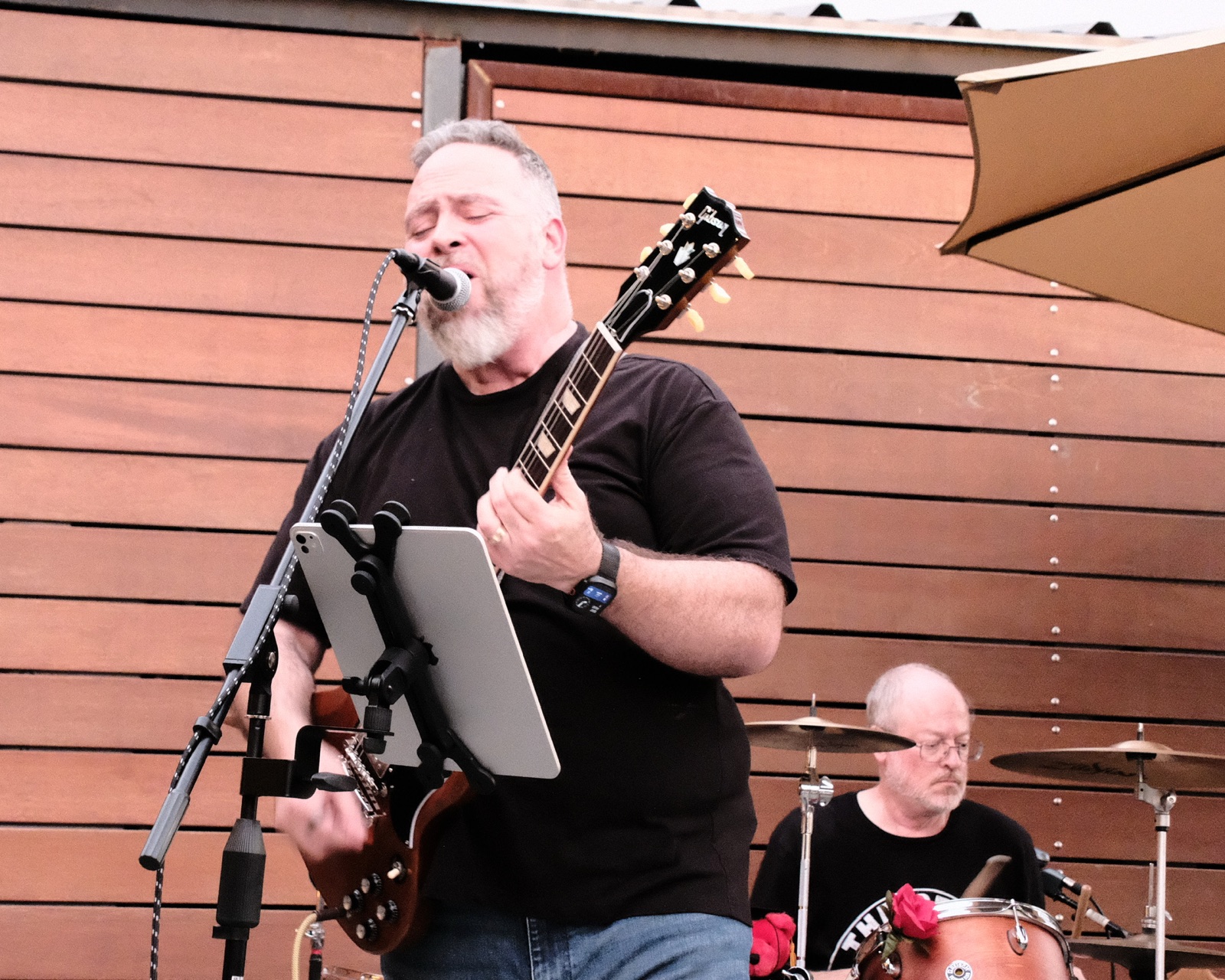 Guitarist singing into the mic with a Gibson slung over his shoulder